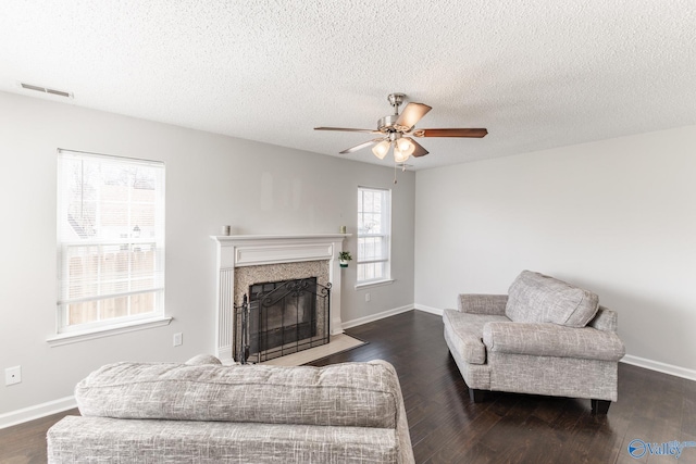 living room with dark wood-style flooring, baseboards, visible vents, and a high end fireplace