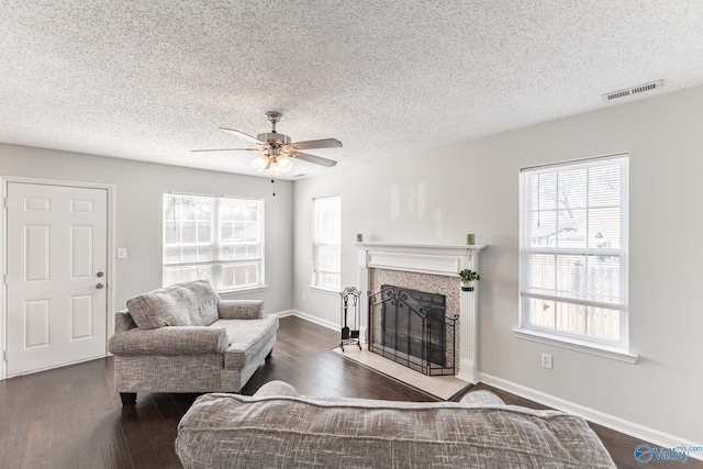 living area featuring a tiled fireplace, wood finished floors, visible vents, and baseboards