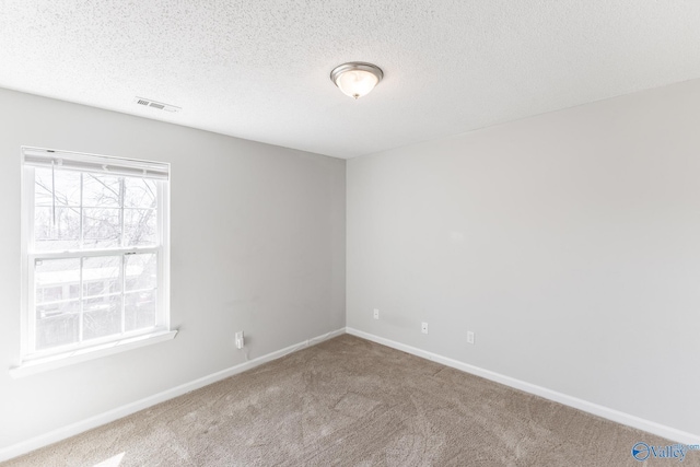 carpeted spare room featuring baseboards, visible vents, and a textured ceiling