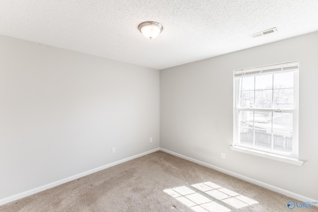 unfurnished room featuring a textured ceiling, carpet, visible vents, and baseboards