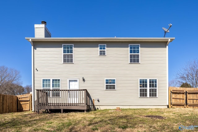 rear view of property with a fenced backyard, a yard, a deck, and a chimney