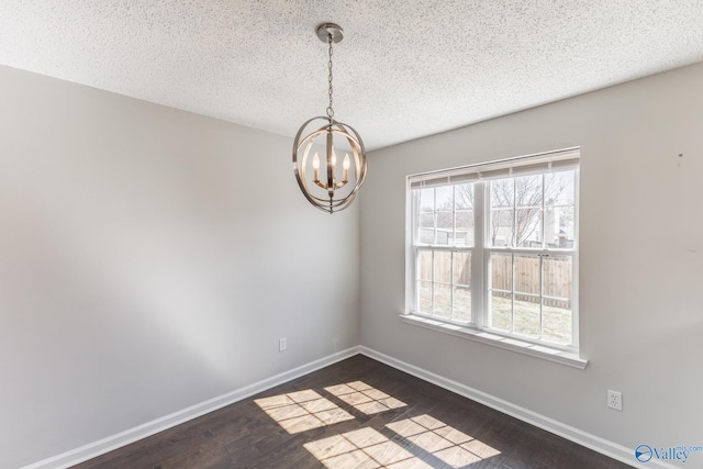 spare room featuring dark wood finished floors, an inviting chandelier, baseboards, and a textured ceiling