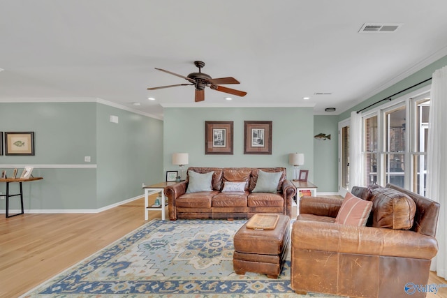 living area featuring ornamental molding, light wood-type flooring, visible vents, and baseboards