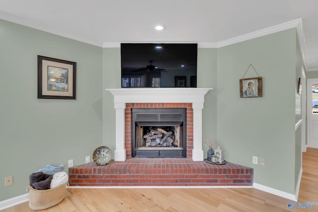 living room featuring ornamental molding, a brick fireplace, baseboards, and wood finished floors