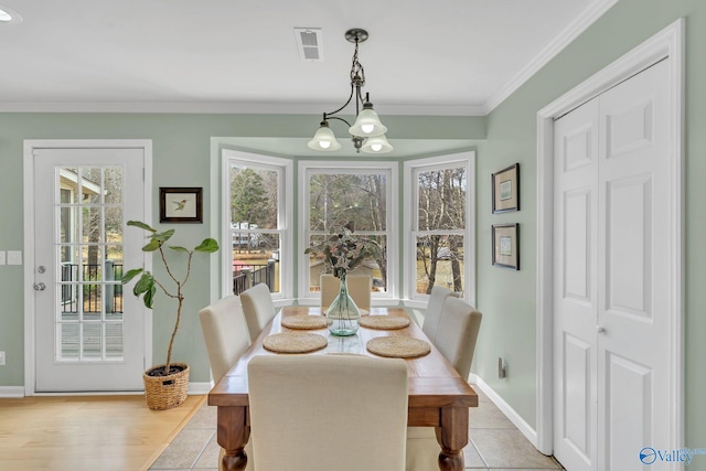 dining space featuring a notable chandelier, crown molding, visible vents, light wood-type flooring, and baseboards