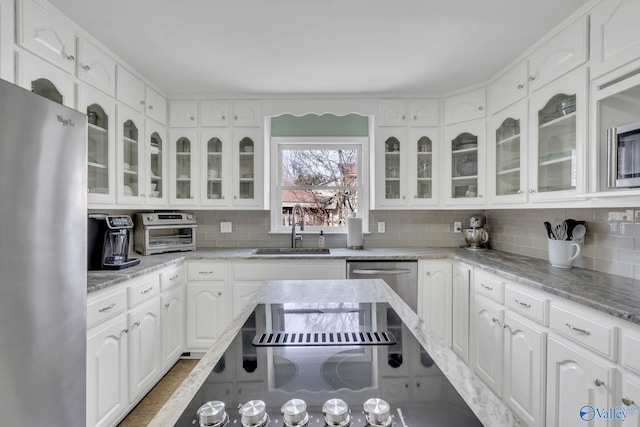 kitchen with stainless steel appliances, glass insert cabinets, white cabinets, and a sink