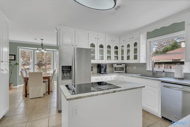 kitchen with white cabinets, glass insert cabinets, appliances with stainless steel finishes, a center island, and light countertops