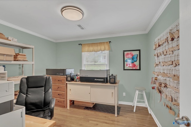 office space with light wood-style floors, visible vents, baseboards, and crown molding