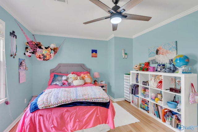 bedroom featuring light wood finished floors, ceiling fan, baseboards, and crown molding