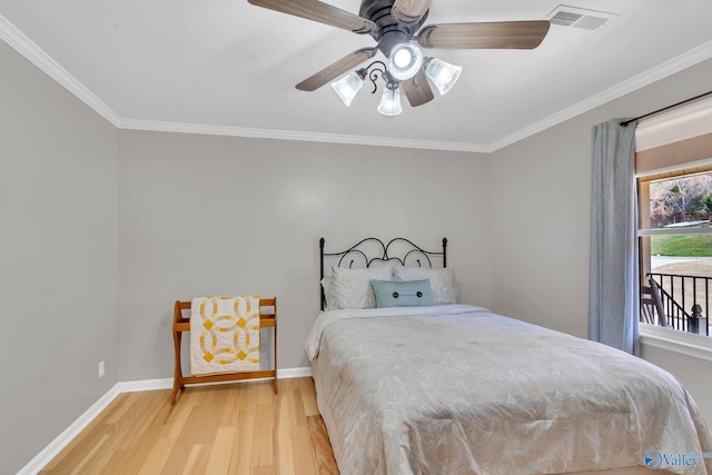 bedroom with visible vents, baseboards, a ceiling fan, wood finished floors, and crown molding