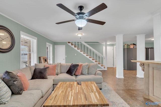 living area featuring crown molding, light tile patterned flooring, ceiling fan, and stairs