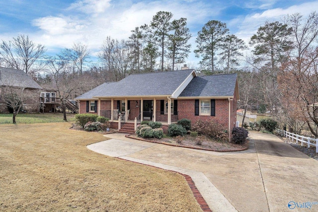 ranch-style home with covered porch, brick siding, driveway, and a front lawn