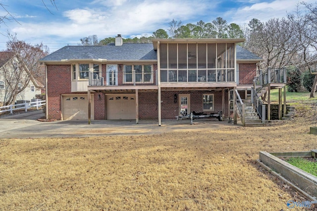 view of front facade with a sunroom, a chimney, stairway, an attached garage, and brick siding