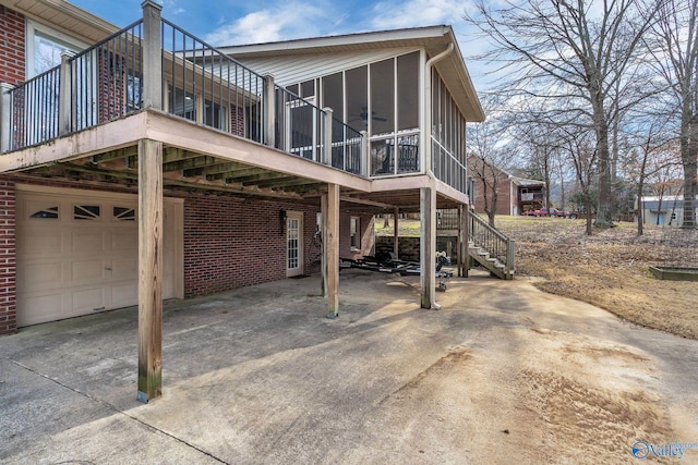 back of house featuring driveway, a sunroom, a carport, and brick siding