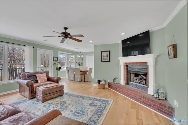 living area with ornamental molding, a brick fireplace, baseboards, and wood finished floors