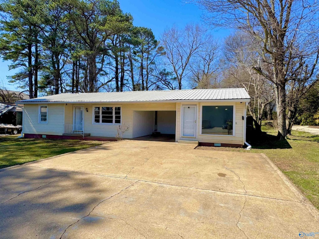 view of front of house featuring metal roof, driveway, an attached carport, and a front lawn