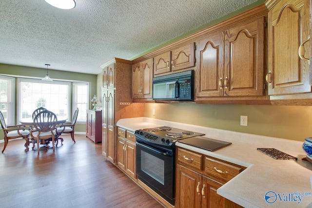 24430 Chadwick Dr, Athens, AL 35613 - kitchen with black appliances, light countertops, a textured ceiling, brown cabinetry, and hanging light fixtures