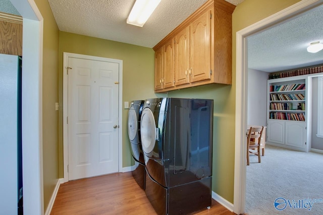 24430 Chadwick Dr, Athens, AL 35613 - laundry room featuring washing machine and dryer, a textured ceiling, cabinet space, and light wood-style flooring