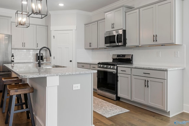 kitchen with appliances with stainless steel finishes, sink, a center island with sink, and gray cabinetry