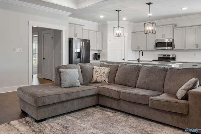 living room featuring ornamental molding, sink, and hardwood / wood-style flooring