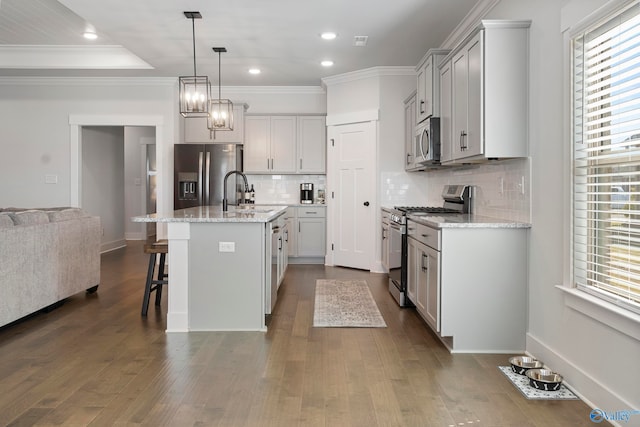 kitchen featuring a center island with sink, appliances with stainless steel finishes, dark hardwood / wood-style floors, and a healthy amount of sunlight