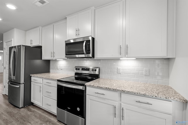 103 Gander Cir, Owens Cross Roads, AL 35763 - kitchen featuring appliances with stainless steel finishes, wood finished floors, white cabinetry, light stone countertops, and decorative backsplash