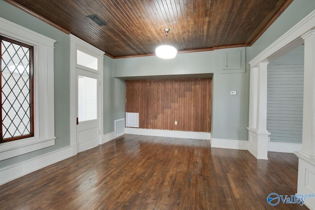 entrance foyer featuring dark wood-type flooring, ornamental molding, wooden ceiling, and ornate columns