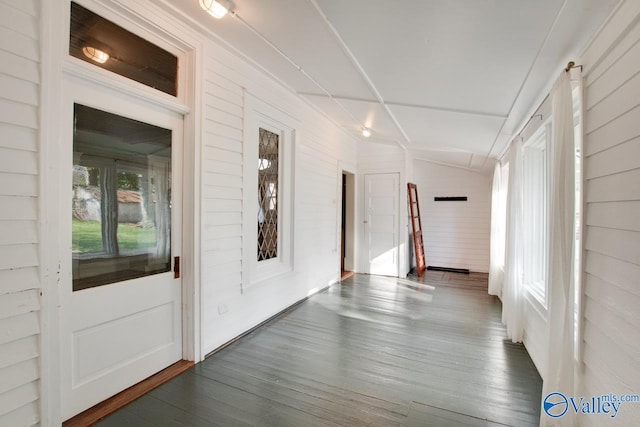 hall with wood walls, vaulted ceiling, and dark hardwood / wood-style floors