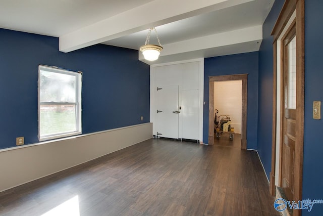 empty room with beamed ceiling and dark hardwood / wood-style flooring