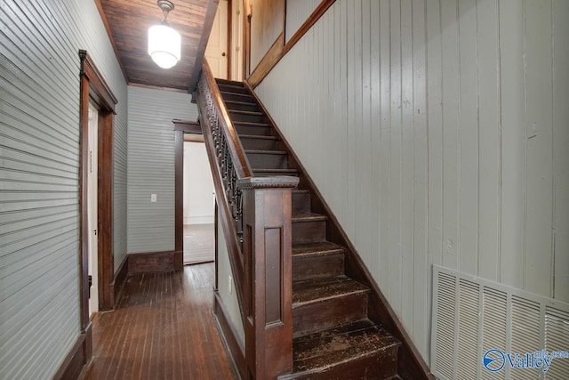 stairway featuring wooden walls, wood ceiling, and hardwood / wood-style floors