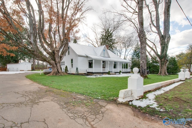 view of front of property featuring a porch, an outbuilding, a front lawn, and a garage