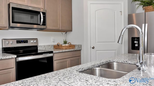 kitchen with appliances with stainless steel finishes, light stone countertops, and sink