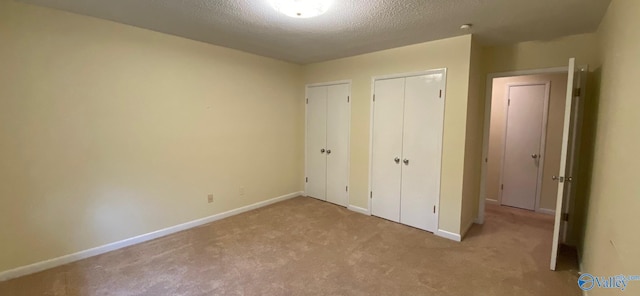 unfurnished bedroom featuring light colored carpet and a textured ceiling