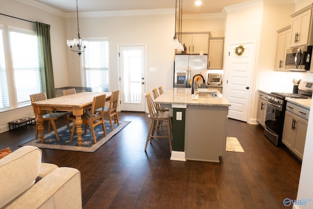 kitchen featuring a kitchen island with sink, sink, decorative light fixtures, light stone counters, and stainless steel appliances