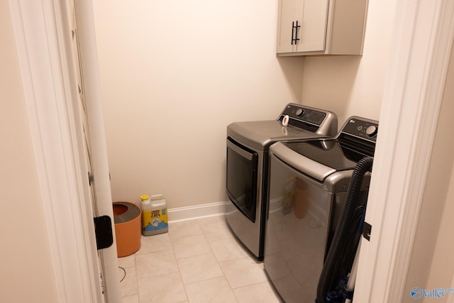 clothes washing area with cabinets, washing machine and dryer, and light tile patterned flooring