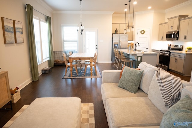 living room featuring dark hardwood / wood-style flooring, an inviting chandelier, ornamental molding, and sink