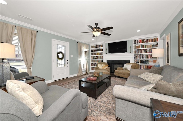 living room featuring ceiling fan, crown molding, built in features, and a wealth of natural light