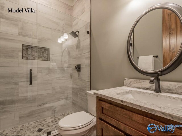 bathroom with a shower with shower door, toilet, and vanity