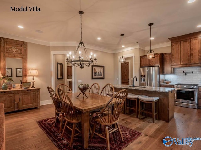 dining room featuring ornamental molding, sink, hardwood / wood-style flooring, and a chandelier