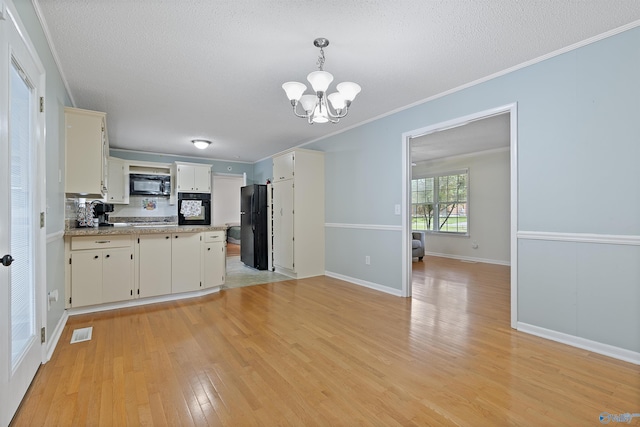 302 Cherry St NW, Hartselle, AL 35640 - kitchen with black appliances, a chandelier, light wood finished floors, light countertops, and white cabinetry