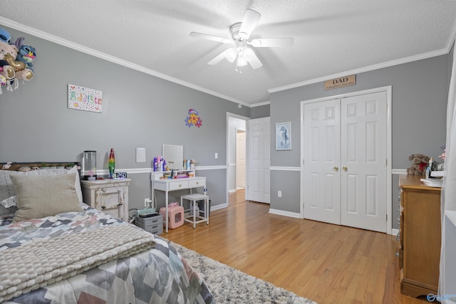 302 Cherry St NW, Hartselle, AL 35640 - bedroom featuring light wood-style flooring, a textured ceiling, ornamental molding, a closet, and a ceiling fan