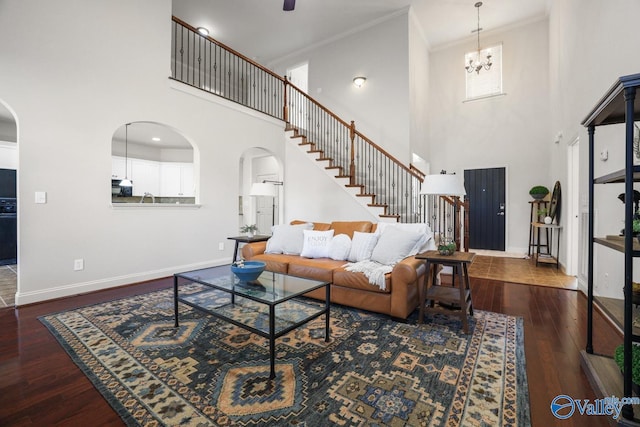 living room featuring a high ceiling, dark hardwood / wood-style floors, an inviting chandelier, and crown molding