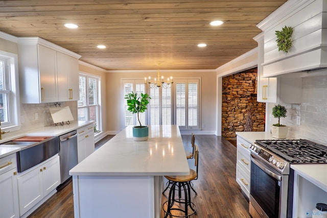 kitchen featuring white cabinetry, hanging light fixtures, a center island, appliances with stainless steel finishes, and crown molding