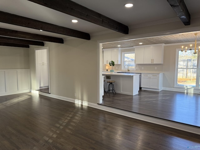 interior space featuring ornamental molding, a notable chandelier, beamed ceiling, sink, and dark hardwood / wood-style floors