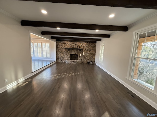 unfurnished living room featuring dark hardwood / wood-style flooring, beamed ceiling, a stone fireplace, and crown molding