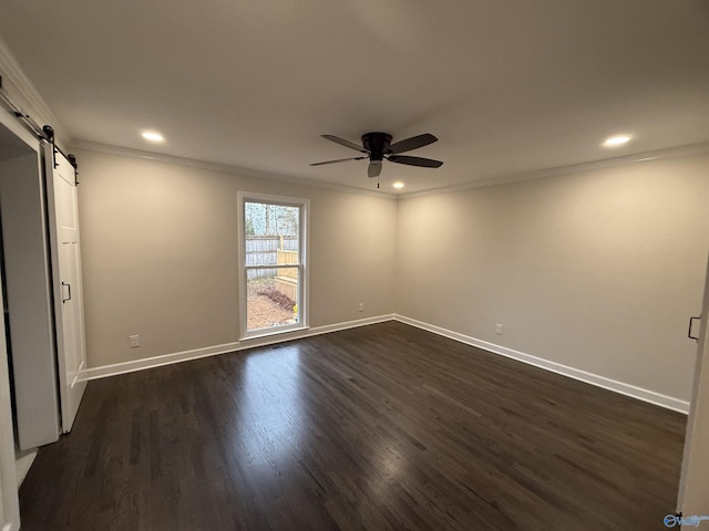 unfurnished room with ceiling fan, dark hardwood / wood-style flooring, a barn door, and ornamental molding