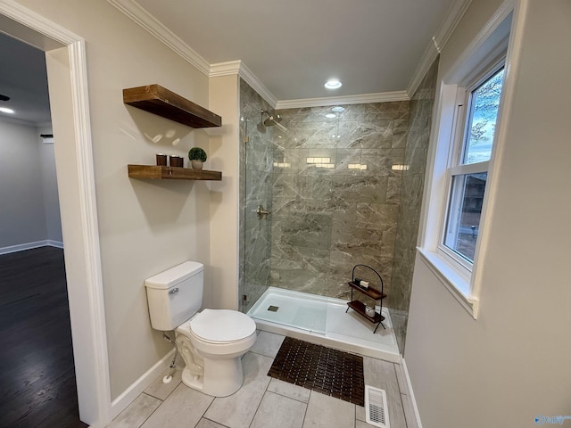 bathroom with toilet, crown molding, and tiled shower