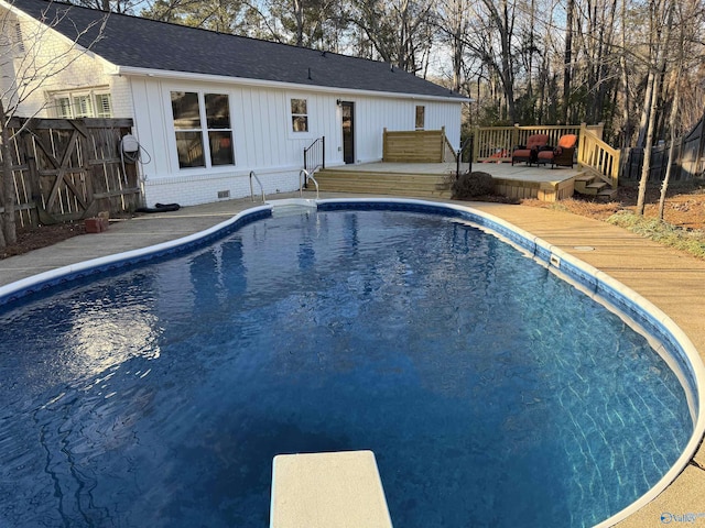 view of pool with a deck and a diving board