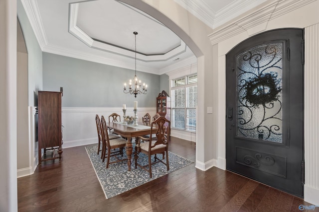 dining room featuring arched walkways, a notable chandelier, dark wood-style flooring, a tray ceiling, and crown molding