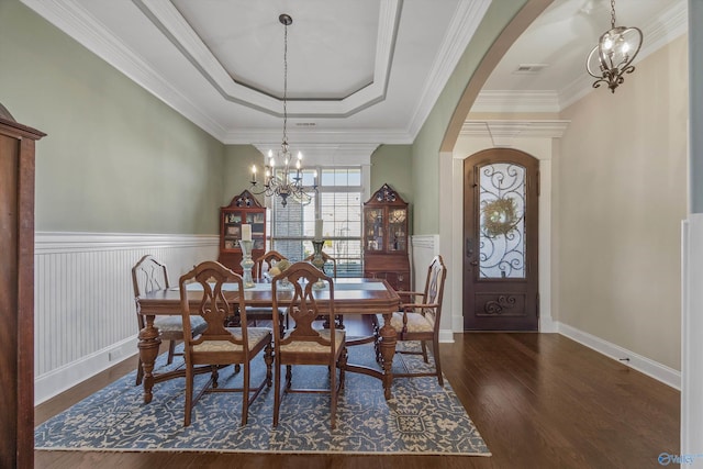 dining room with a chandelier, arched walkways, visible vents, dark wood-style floors, and a tray ceiling